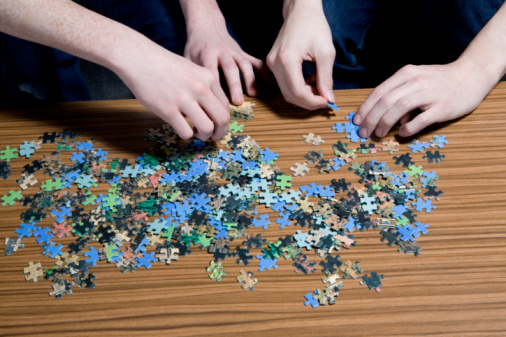 Men putting together puzzle, mid section